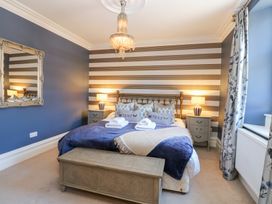 A bedroom with a bed bedside tables lamps a wooden chest a mirror and curtains at Allendale House in Armathwaite