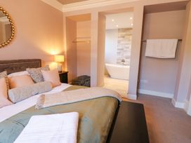 A bedroom with a bed pillows and blankets beside a bathroom with a bathtub at Allendale House in Armathwaite