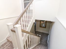 A staircase with patterned carpet and white railing leading down to a hallway with a mirror on the wall at Allendale House in Armathwaite