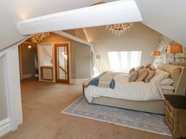 A bedroom with a bed pillows bedside table and chandelier at Allendale House in Armathwaite