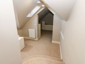 A hallway with carpeted stairs leading to a carpeted room with white dressers and a radiator under a skylight at Allendale House in Armathwaite
