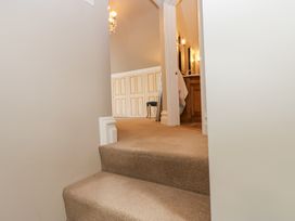 A carpeted staircase leading to a hallway with a wooden vanity and a chair at Allendale House in Armathwaite