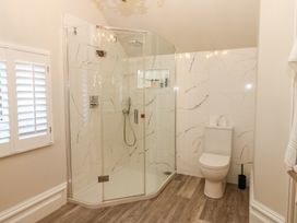 A bathroom with a glass shower enclosure and a toilet on a wood floor at Allendale House in Armathwaite