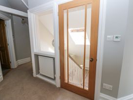A hallway with a wooden glass door leading to a staircase and a wall radiator below a window at Allendale House Armathwaite