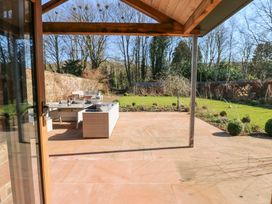 An outdoor patio with wicker furniture and a garden with trees and shrubs at Allendale House in Armathwaite