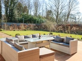 An outdoor patio with cushioned wicker seating and a glass table with glasses and a bottle on it at Allendale House in Armathwaite