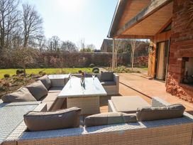 An outdoor patio with wicker furniture and a glass table with champagne glasses and a bottle at Allendale House in Armathwaite