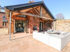 An outdoor patio with a covered seating area and glass table at Allendale House in Armathwaite