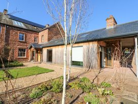 An exterior view of a brick and wood house with a small garden and trees at Allendale House in Armathwaite