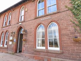 Exterior of a brick building with arched windows and a doorway with signs reading fox and pheasant inn and robinsons