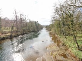 A river flowing between trees on both banks with a sandy shore on the right at Allendale House in Armathwaite