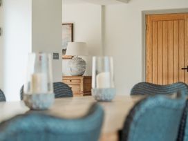 A dining area with a wooden table and chairs with candles on table and a wooden door and sideboard with a lamp at The Old Watermill in Beadnell