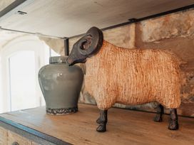A wooden shelf with a ceramic ram figurine and a grey vase at The Old Watermill in Beadnell