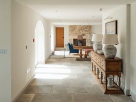 A hallway with stone floor and wooden sideboard with lamps leading to a living area with a stone fireplace at The Old Watermill in Beadnell
