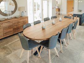 A dining room with a wooden table and ten gray chairs at The Old Watermill in Beadnell