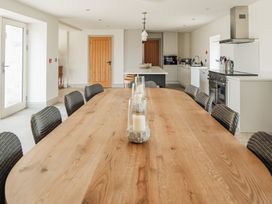 A dining room with a long wooden table surrounded by chairs and candles on the table at The Old Watermill in Beadnell