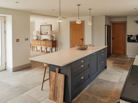 A kitchen with an island countertop wooden stools and wooden doors at The Old Watermill in Beadnell