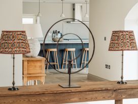 A kitchen with three wooden stools by a blue island and decorative lamps with patterned shades at The Old Watermill in Beadnell