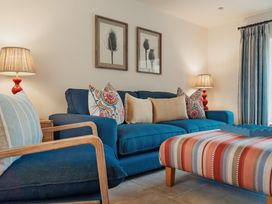 A living room with blue sofas patterned cushions a striped ottoman and two lamps at The Old Watermill in Beadnell