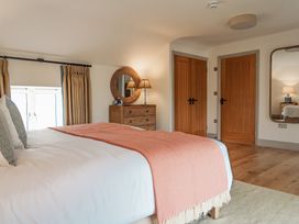 A bedroom with a bed with a blanket a wooden dresser a round mirror two wooden doors and a large wall mirror at The Old Watermill in Beadnell