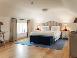 A bedroom with a bed a blue bench two bedside tables with lamps and a window with curtains at The Old Watermill in Beadnell
