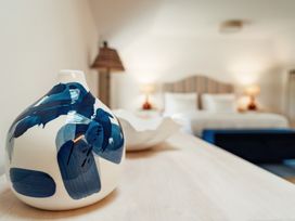 A ceramic vase with blue brush strokes on a wooden surface in a bedroom with a bed and lamps at The Old Watermill in Beadnell