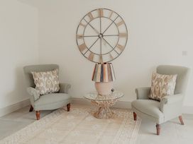 A seating area with two armchairs a side table with a lamp and a large wall clock at The Old Watermill in Beadnell