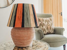 A table lamp with a striped shade on a glass table with stones and an armchair with a patterned cushion at The Old Watermill in Beadnell