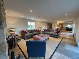 A living room with two gray sofas and a blue chair around a pink ottoman and table lamps at The Old Watermill in Beadnell