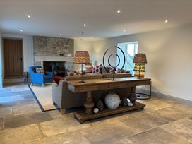 A living room with a stone fireplace a wooden console table with lamps a blue armchair and a large sofa at The Old Watermill in Beadnell