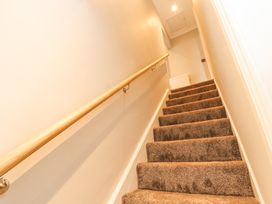 A carpeted staircase with a wooden handrail and a radiator at the top at Grace House in Silloth