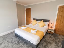 A bedroom with a double bed yellow pillows and folded towels on a bed runner at Grace House in Silloth