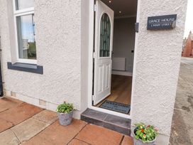 An open white door showing a welcome mat and flower pots outside at Grace House in Silloth
