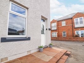 A building entrance with a white door and window with pots on either side at Grace House in Silloth