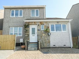 The front view of a two-story house with multiple windows a white door stone and pebble dash exterior and a driveway at Ty Copr in Amlwch