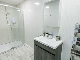 A bathroom with a glass enclosed shower on the left a sink with a cabinet and a wall mirror above at Ty Copr in Amlwch