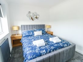 A bedroom with a bed with blue floral bedding two bedside tables with lamps and a decorative mirror on the wall at Ty Copr in Amlwch