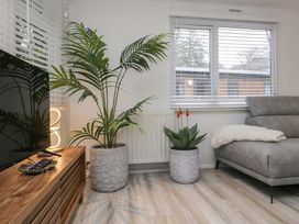 A living room with a television and plants at Cosy Corner White Cross Bay near Troutbeck Bridge