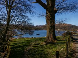 A view of a lake with a tree and boat at Cosy Corner White Cross Bay near Troutbeck Bridge