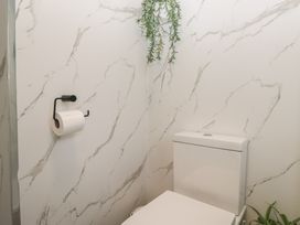 A bathroom with a toilet and toilet paper holder at Cosy Corner near White Cross Bay