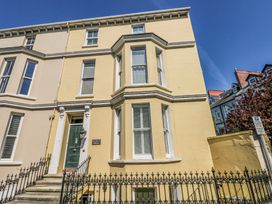 A yellow three-story house with a green door and white-trimmed windows at Hereford House in Tenby