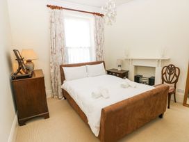 A bedroom with a double bed next to a window with floral curtains at Hereford House in Tenby