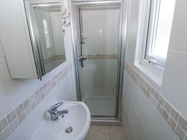 A bathroom with a shower enclosure a washbasin with a faucet a window and a wall-mounted mirror cabinet at Hereford House in Tenby