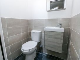 A small bathroom with a white toilet and a wall-mounted sink with a cabinet at Hereford House in Tenby