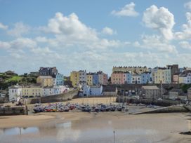 A harbor with boats on sand and colorful buildings in the background at Hereford House in Tenby