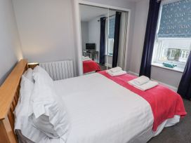 A bedroom with a bed and mirror at Kennie Cottage in Seahouses