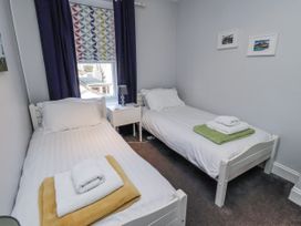 A bedroom with two beds and a nightstand at Kennie Cottage in Seahouses
