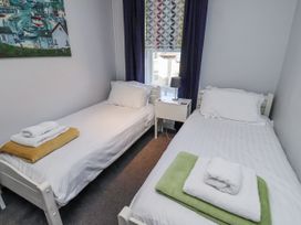 A bedroom with two single beds and a bedside table at Kennie Cottage, Seahouses