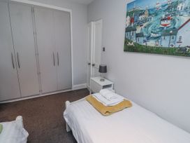 A bedroom with a bed, wardrobe, and side table at Kennie Cottage, Seahouses