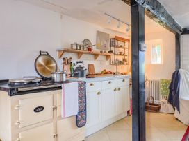 A kitchen with a stove and shelves at Hole House in Branscombe